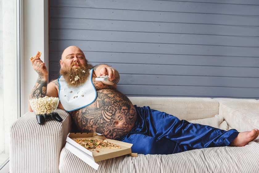 Relaxed thick guy entertaining with pizza and television